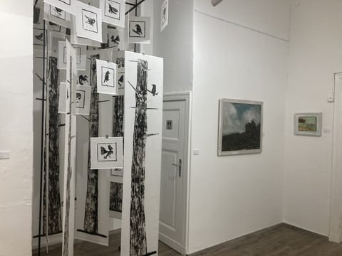 View through the exhibition room with hanging panels and paintings